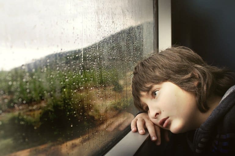 Child looking out rainy window