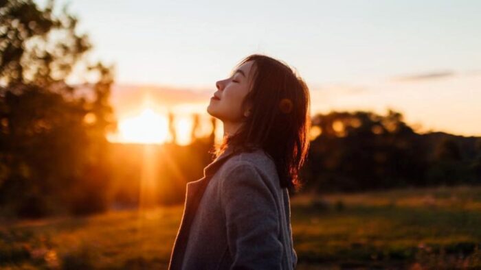 Woman standing at sunset with eyes closed